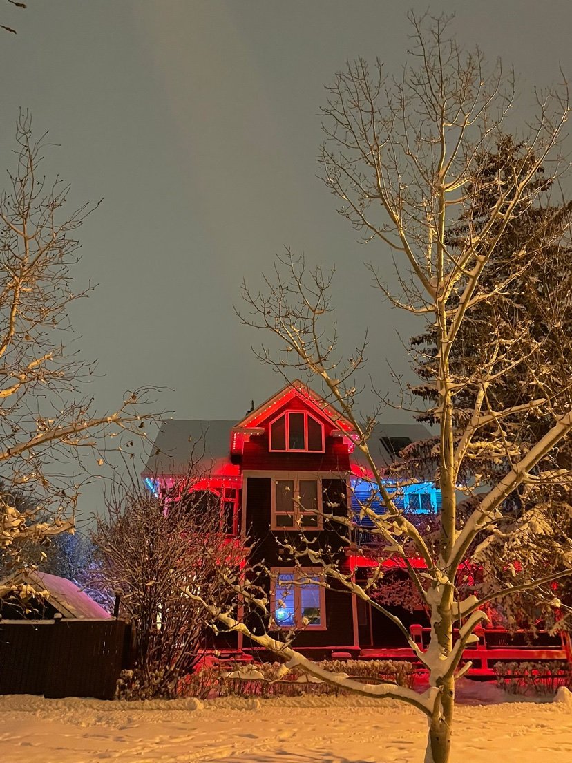 Design inspiration: home with red roofline holiday lighting at night in the snow