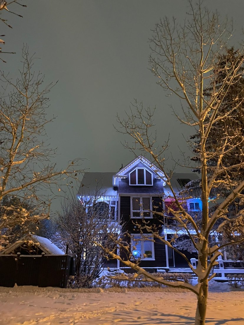 Design inspiration: home with ice-white and blue roofline holiday lighting at night in the snow