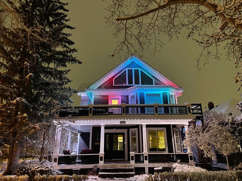 Design inspiration: home with multicolor roofline and warm white porch holiday lighting at night in the snow